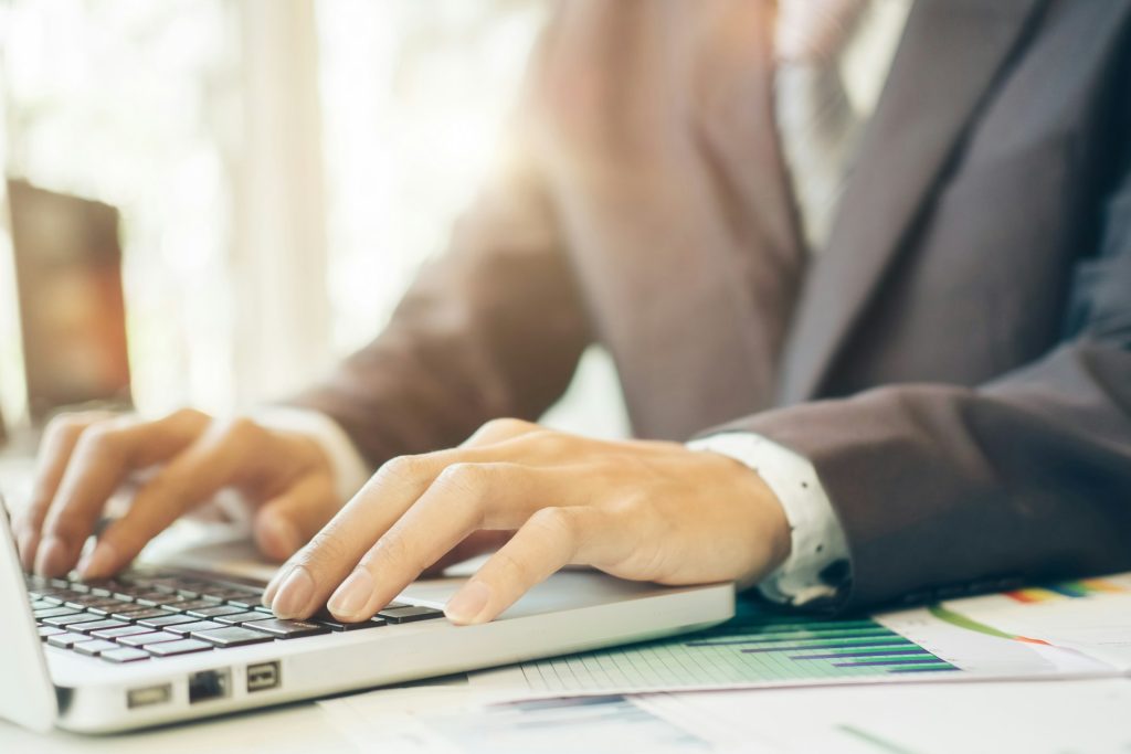 Typing on a laptop with documents and financial charts on the desk, representing professional financial planning services at Daybook Financial Group.