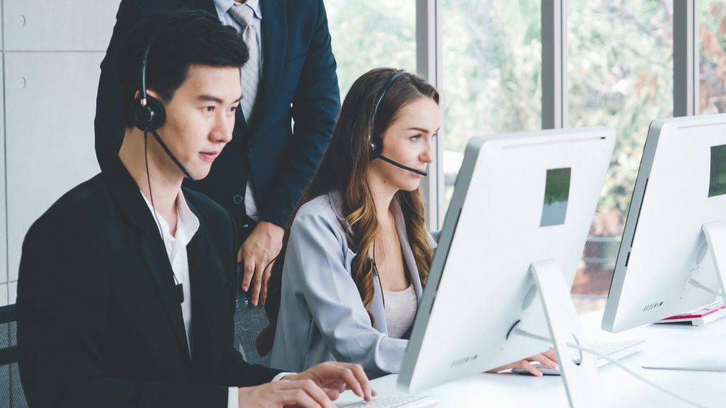 Call center customer service representatives working at computers with headsets in a modern office for financial support.