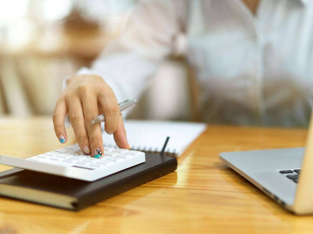 Calculator and financial planning tools on wooden desk, representing professional financial services.