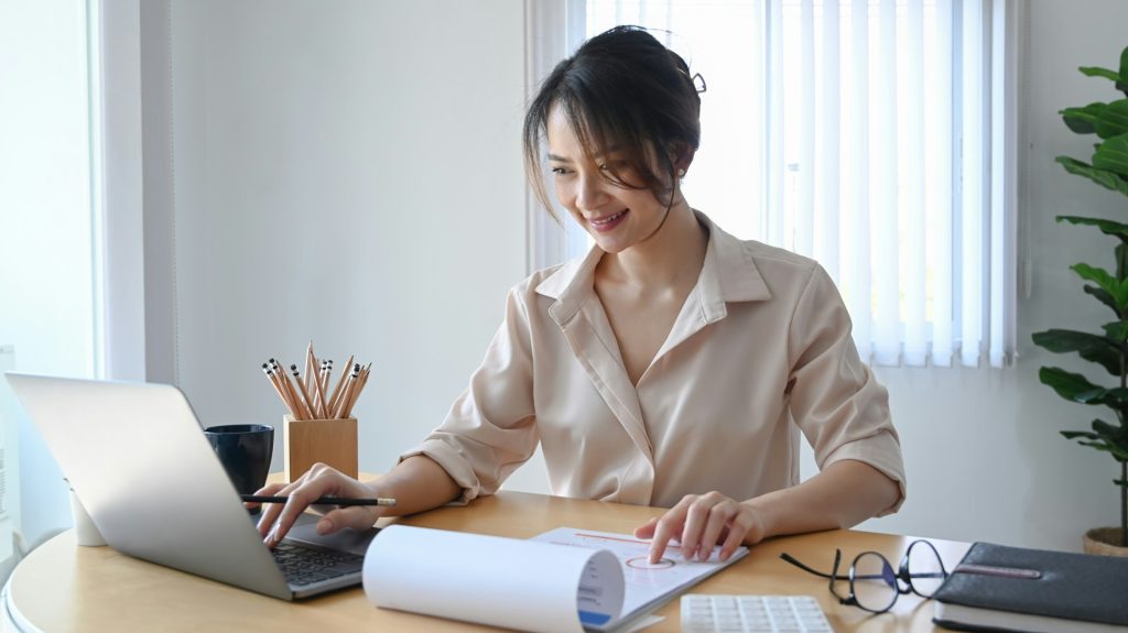 Professional woman working on financial documents at her desk with a laptop, representing Daybook Financial Group services for financial planning and advisory.