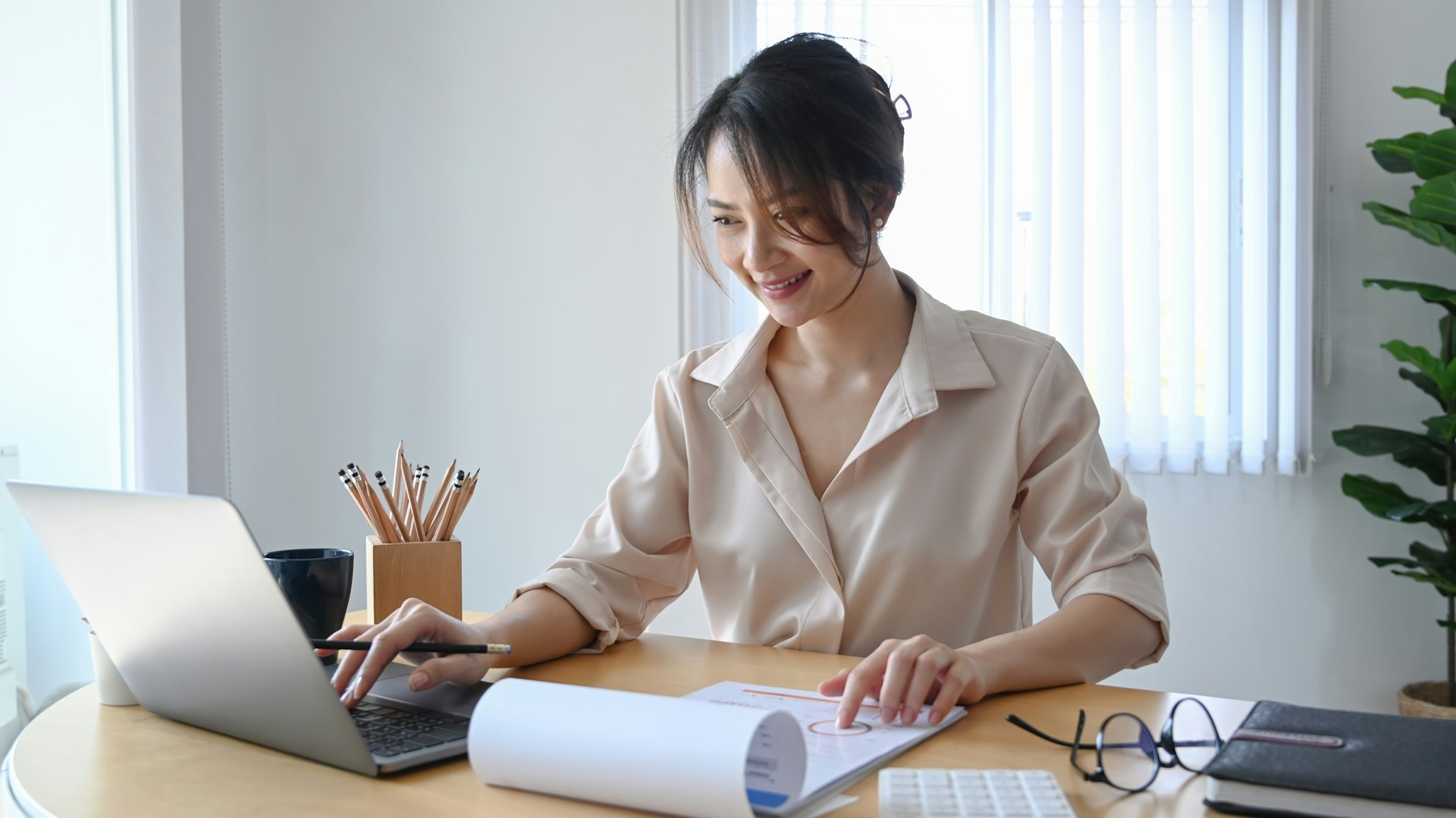 Professional woman working on financial documents at her desk with a laptop, representing Daybook Financial Group services for financial planning and advisory.